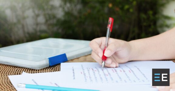 a person marking a document with a red pen