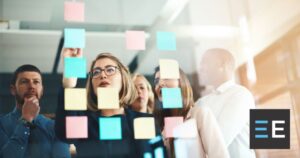 Coworkers adjusting sticky notes on a board
