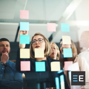 Coworkers adjusting sticky notes on a board
