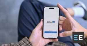A person holding a smartphone displaying the LinkedIn log in page