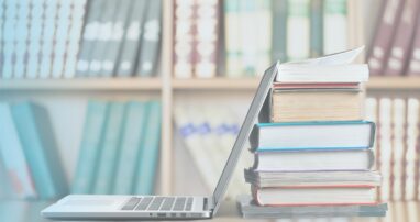An open laptop against a stack of books