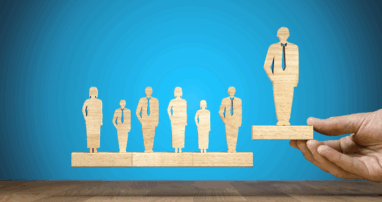 A hand picks up a wooden cutout of a person from a line of 7 wooden cutouts