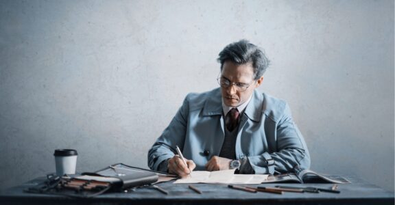 A person performs business writing at a cluttered desk