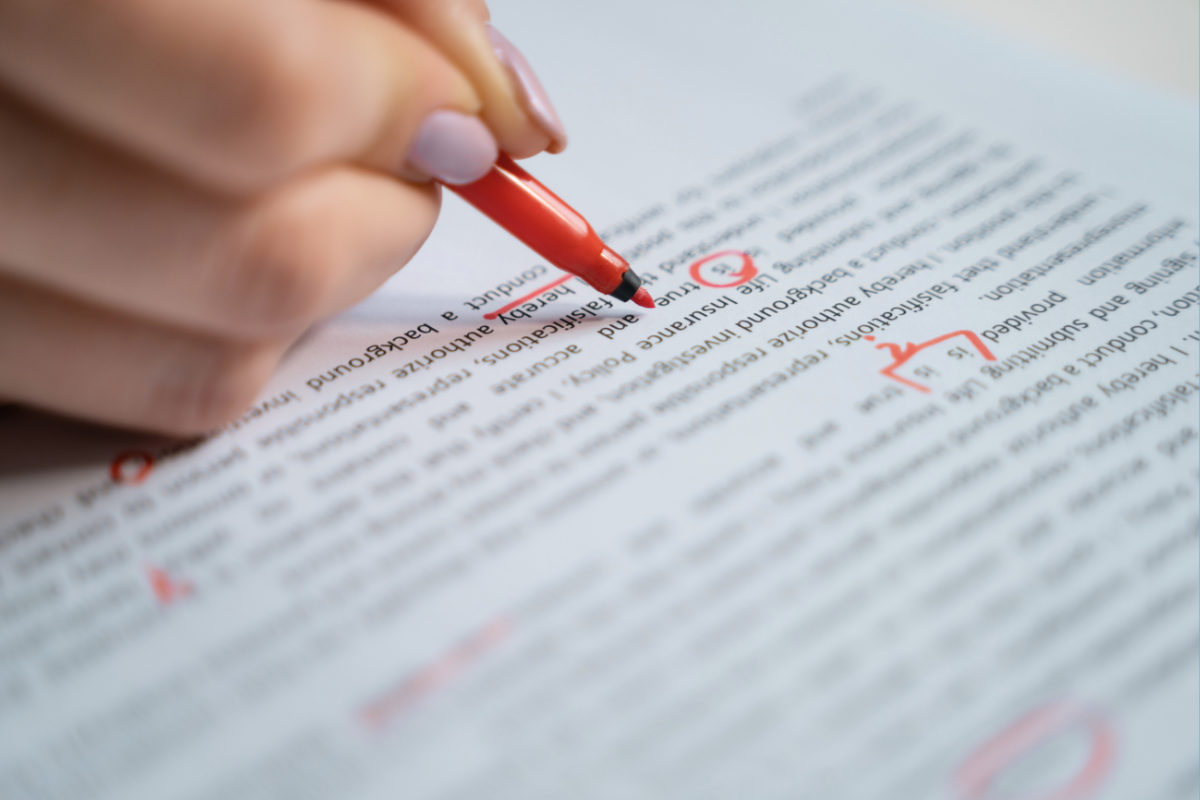 A person marks up a document with a red pen