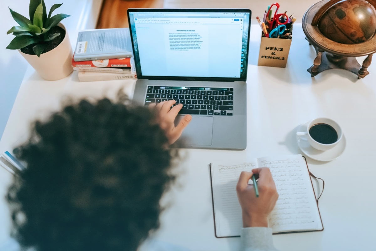 A business writer uses a notebook and laptop