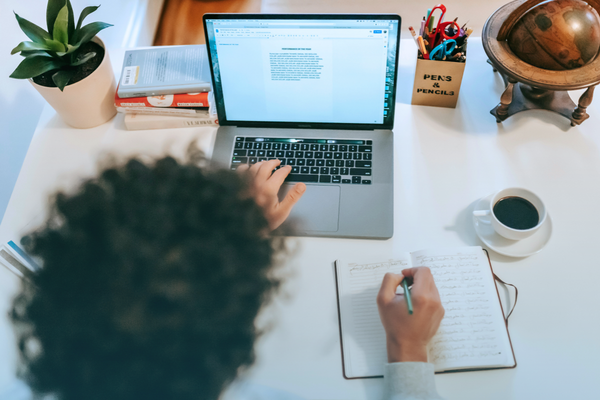 A business writer uses a notebook and laptop