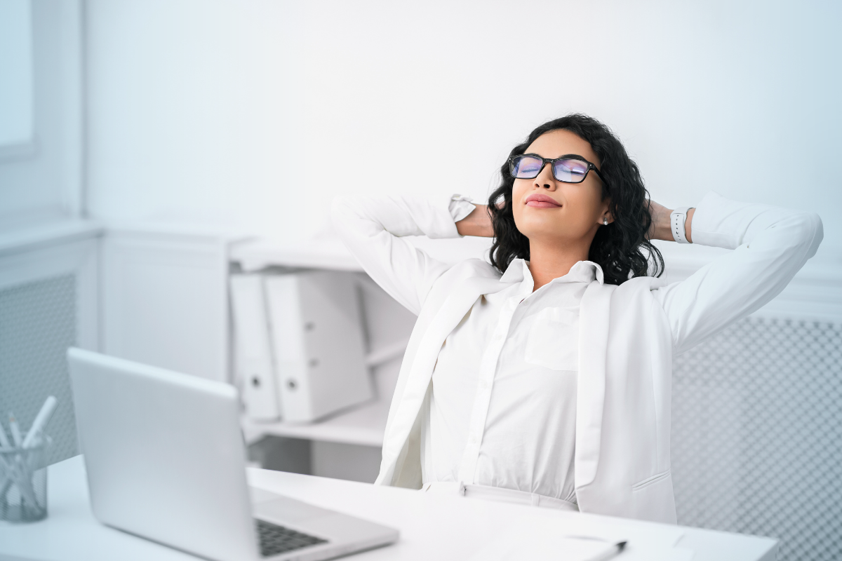 A business writer leans back at their desk to relax in front of a laptop