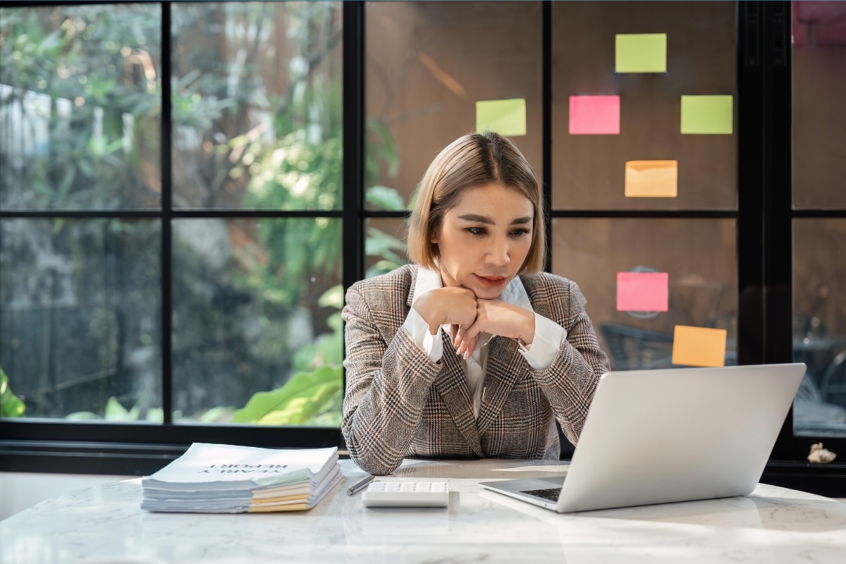 A person working at a desk considers thought leadership content on their laptop