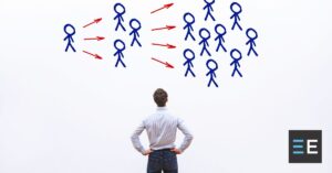 A person looking at a drawing of groups of stick figures connected by arrows on a wall.