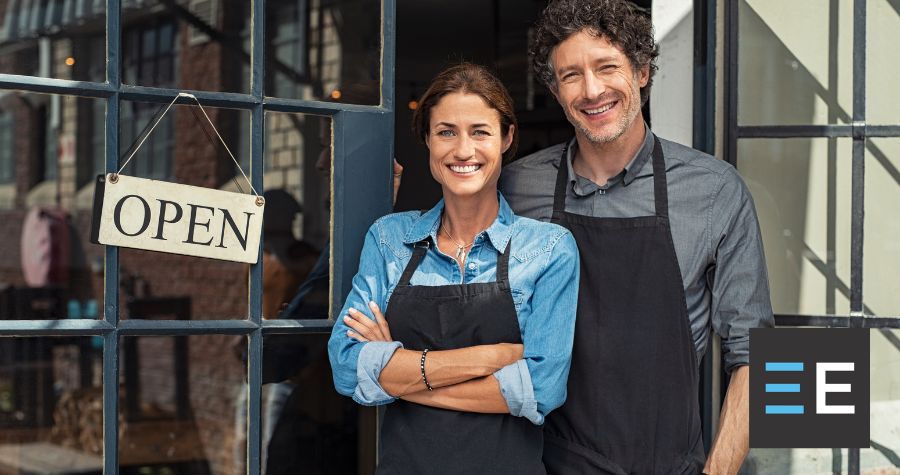 Two people smiling next to an open sign