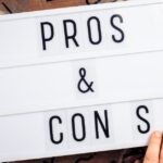 A person adjusting letters on a small marquee. It reads Pros & Cons