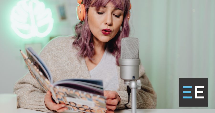 A person wearing headphones reading from a book into a microphone