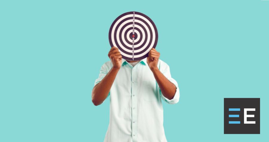 A person standing in front of a blue wall holding a target in front of their face