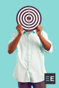 A person standing in front of a blue wall holding a target in front of their face