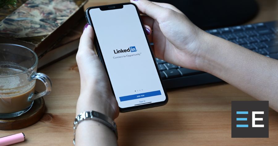 A person holding a smartphone displaying the LinkedIn login page