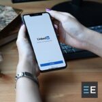 A person holding a smartphone displaying the LinkedIn login page